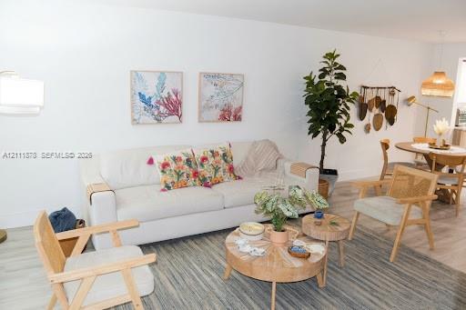 Open-concept area featuring neutral wall tones, wood-finish flooring, and two woven pendant light fixtures Open-concept area featuring neutral wall tones, wood-finish flooring, and two woven pendant light fixtures