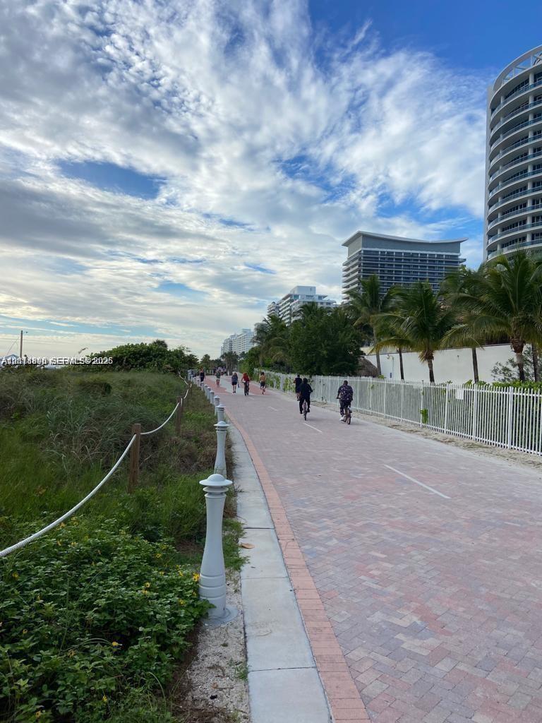 Paved multi-use path featuring decorative bollards, coastal landscaping, and high-rise architecture