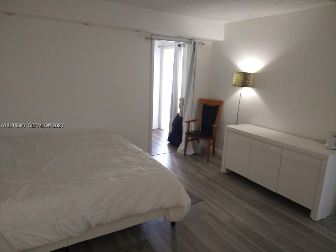 Neutral interior featuring wood-finish flooring and a doorway leading to a secondary space
