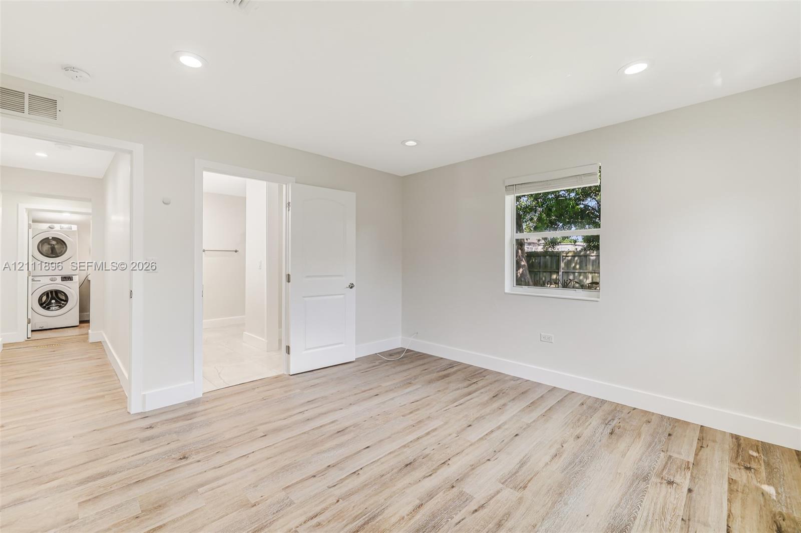 Neutral-toned interior featuring wood-finish flooring, recessed lighting, and a single-hung window with a roller shade