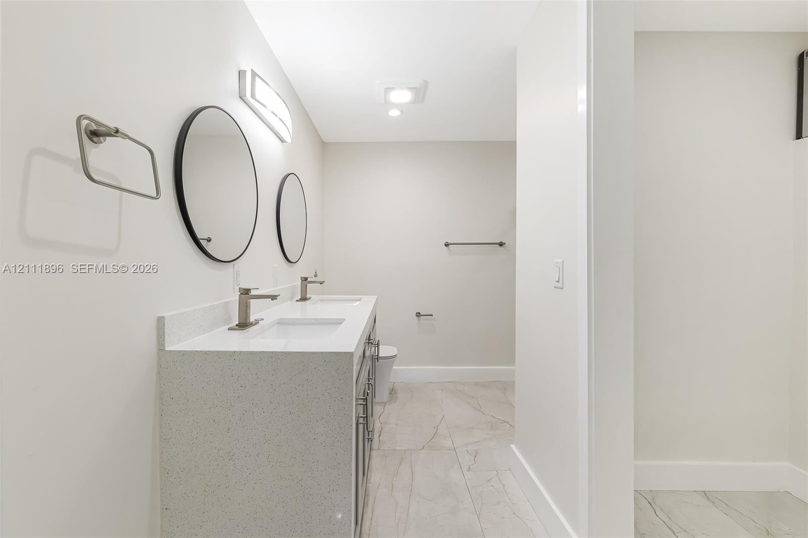 Double vanity featuring a light-toned countertop, rectangular undermount sinks, and wall-mounted circular mirrors