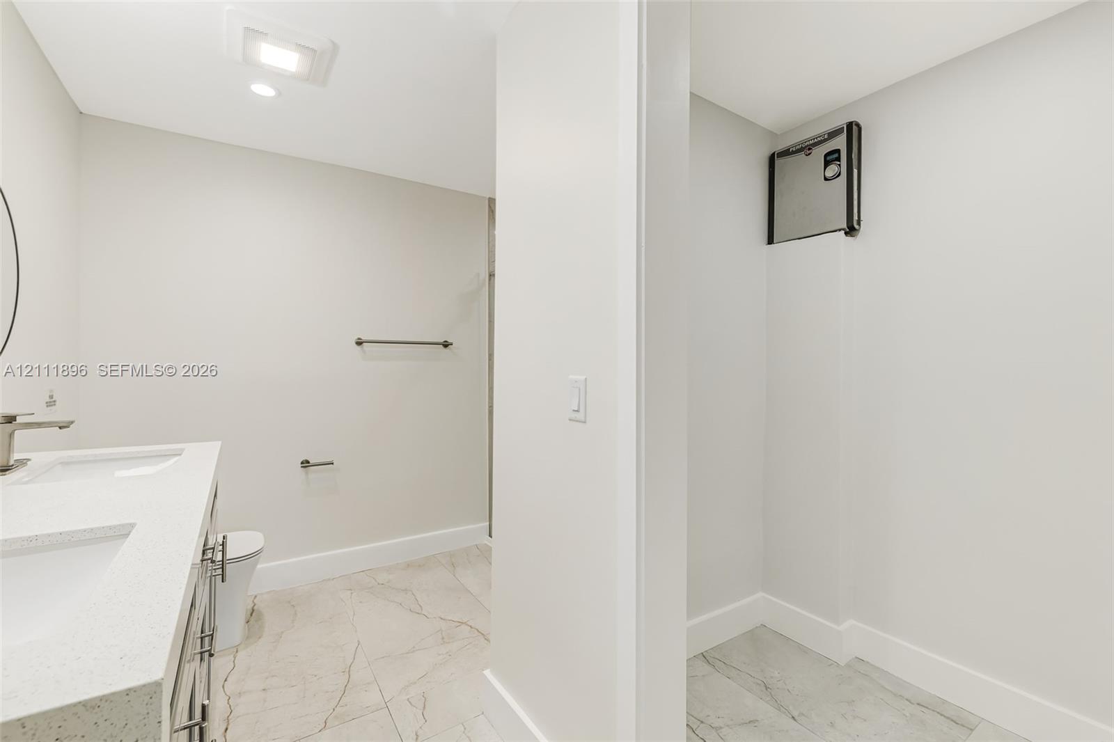 Dual-sink vanity with a quartz countertop, recessed ceiling lighting, and tile flooring featuring a veined pattern