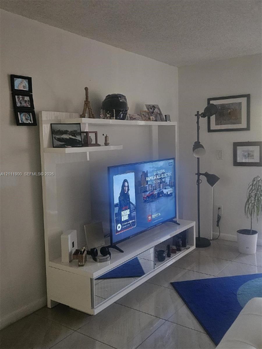 Built-in white entertainment center featuring a high-gloss finish, mirrored drawer fronts, and open display shelving, paired with tile flooring
