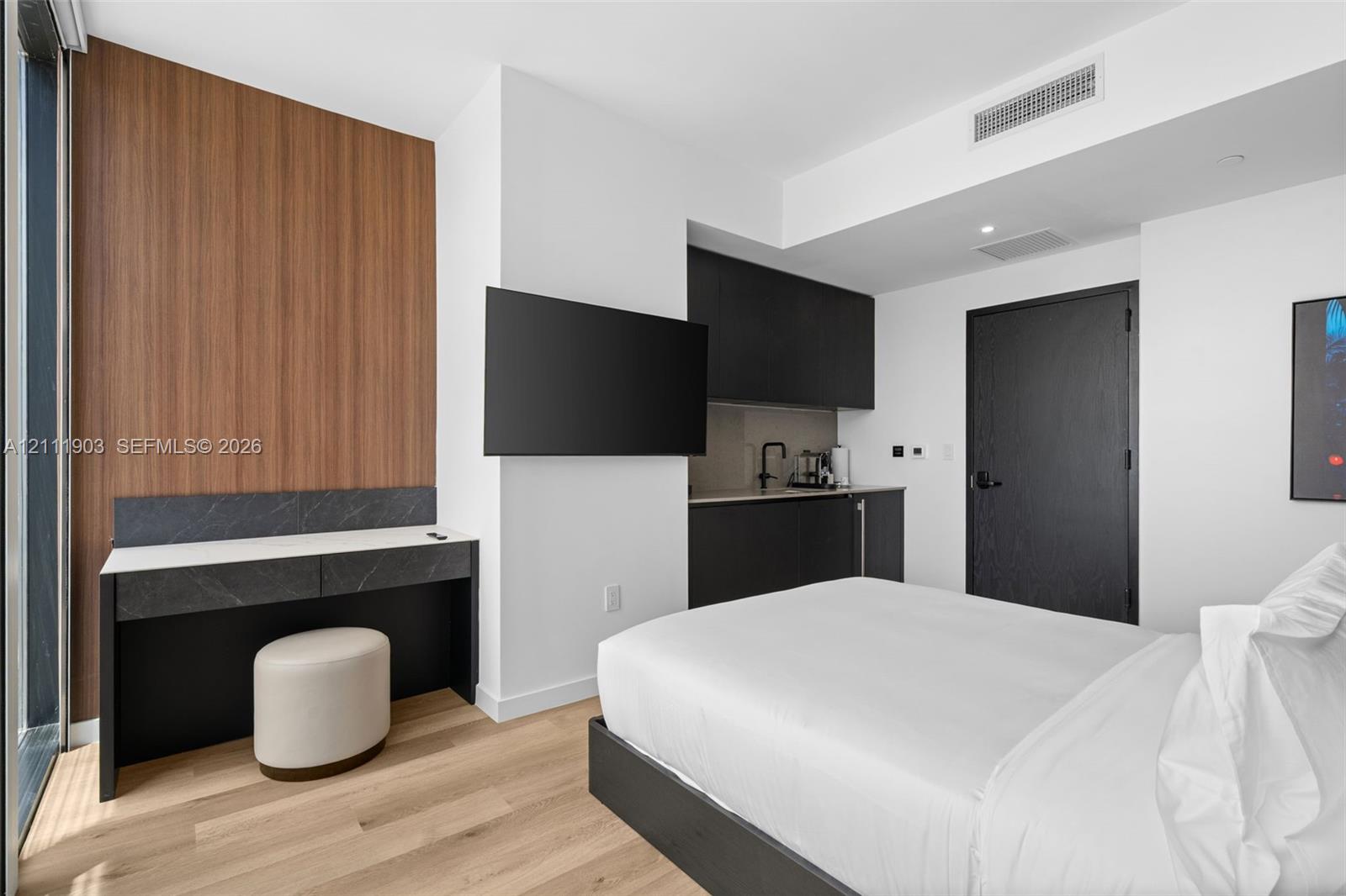 Built-in desk with stone-finish surface, wood-finish flooring, matte black cabinetry, and wood-paneled accent wall
