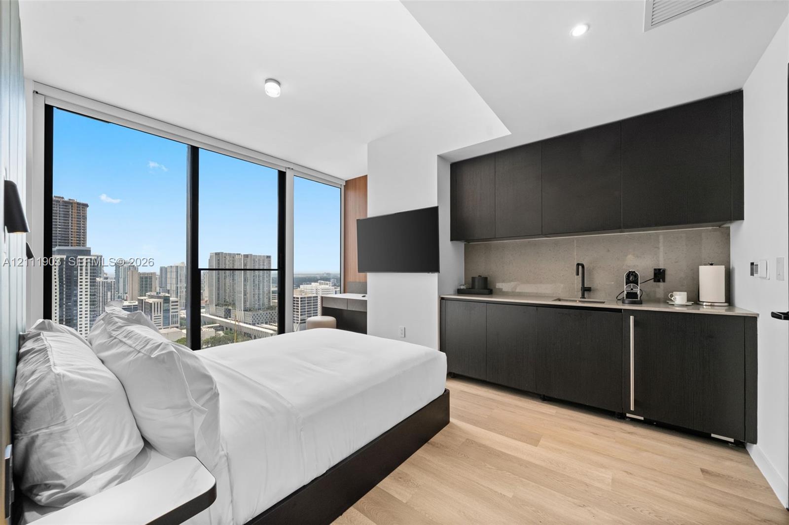 Floor-to-ceiling windows, wood-finish flooring, custom dark cabinetry, stone-finish backsplash, and recessed lighting
