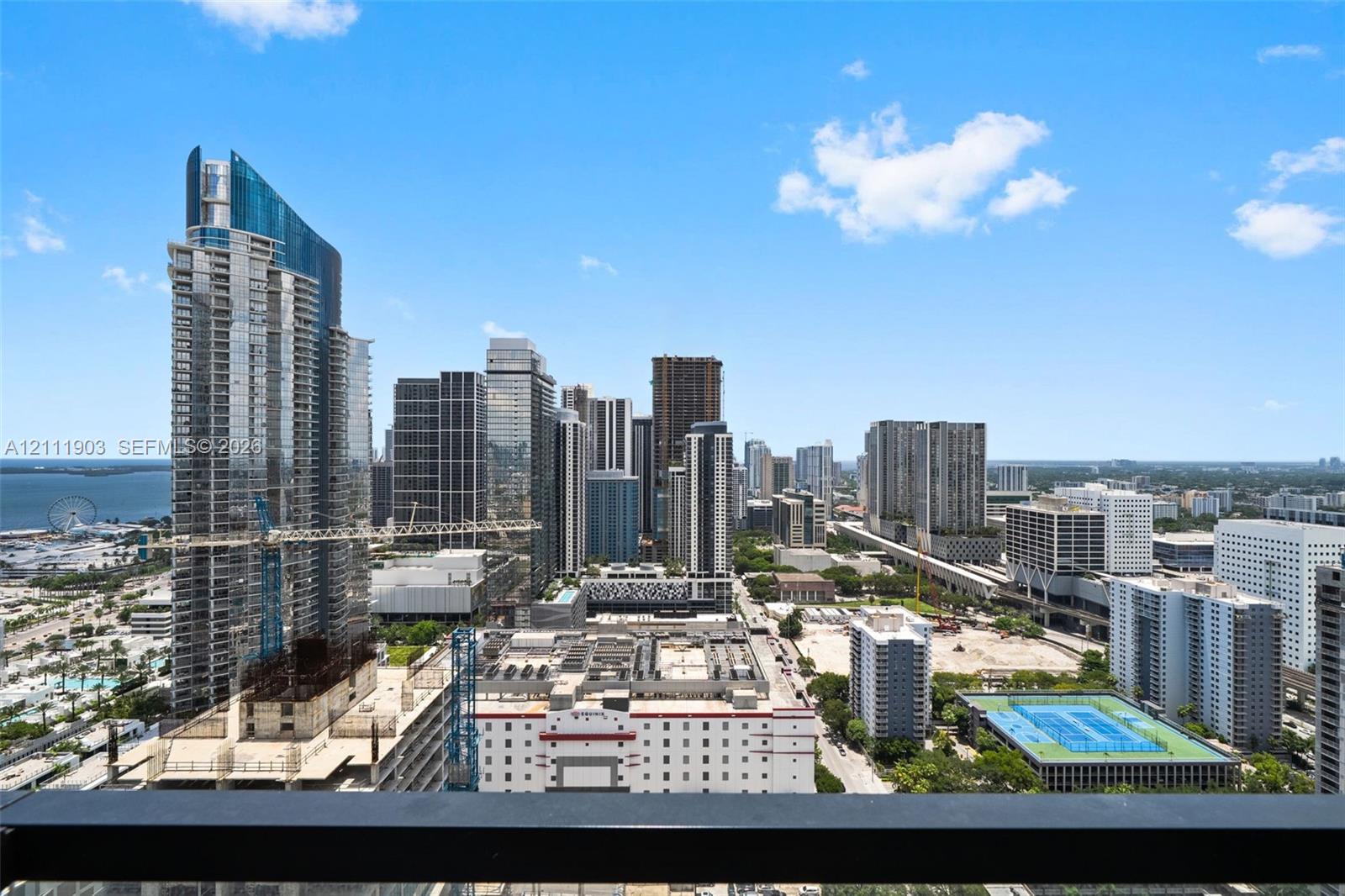 Elevated urban perspective featuring expansive city skyline, coastal waters, and high-rise architecture