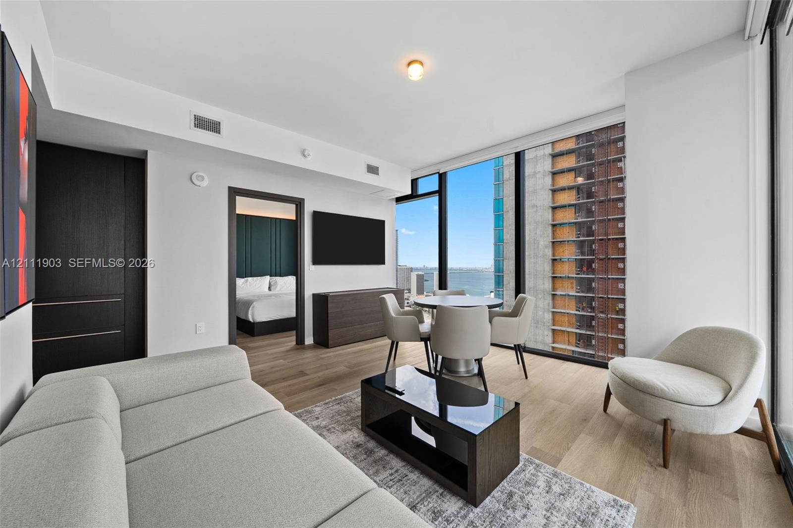 Floor-to-ceiling windows, wood-finish flooring, and dark-toned built-in cabinetry