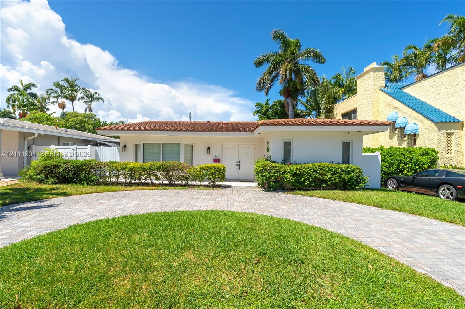 Single-story exterior featuring a terracotta-tiled roof, paver driveway, manicured landscaping, and double-entry front doors Single-story exterior featuring a terracotta-tiled roof, paver driveway, manicured landscaping, and double-entry front doors