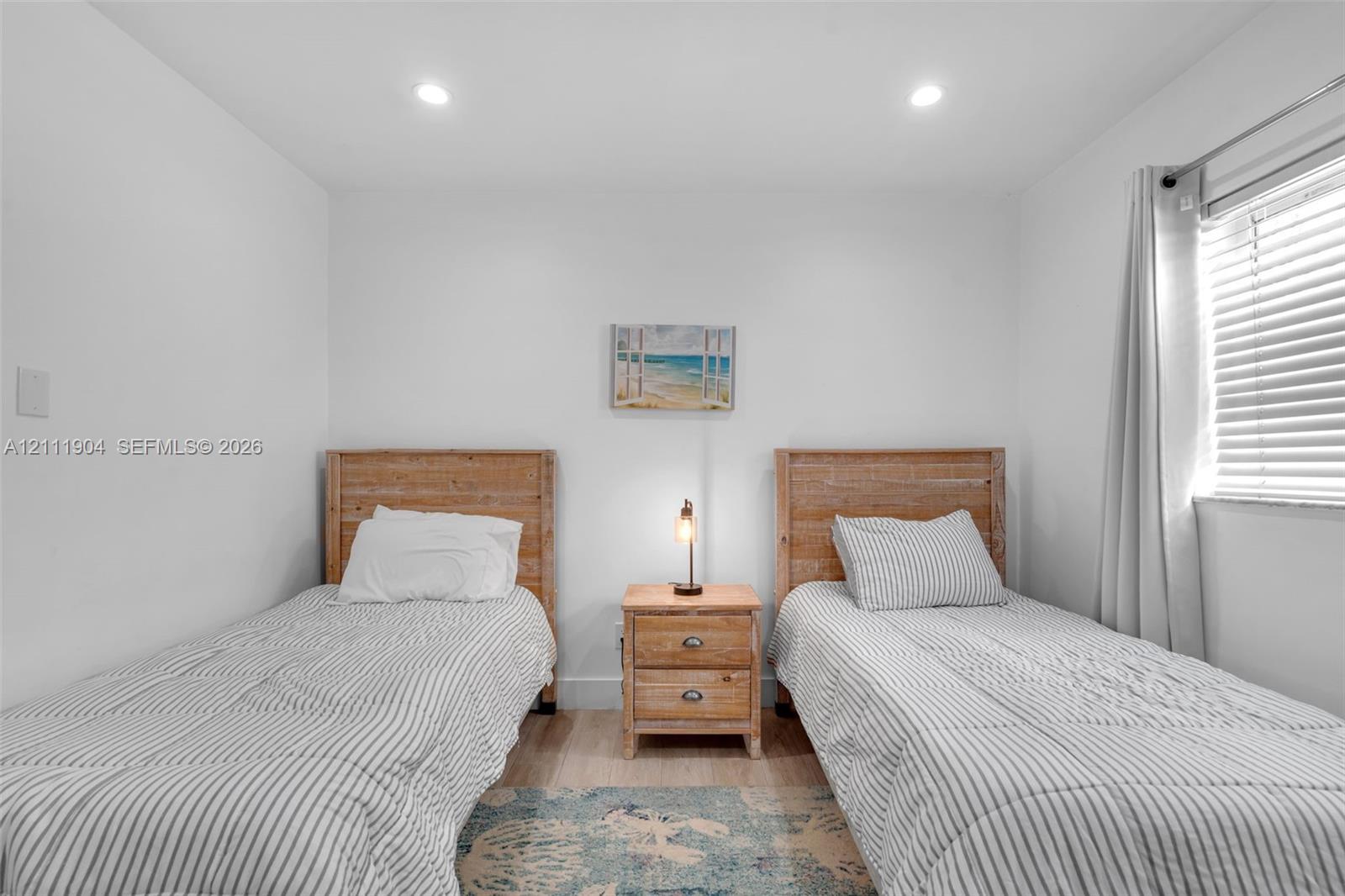 Neutral-toned room featuring recessed ceiling lighting, wood-finish flooring, and a horizontal window with adjustable blinds