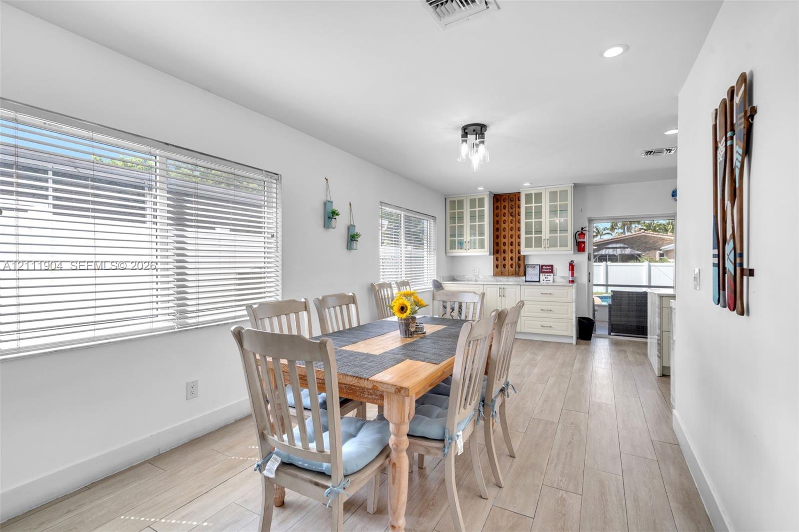 Ceramic tile flooring, white shaker-style cabinetry with glass-front uppers, recessed ceiling lighting, and horizontal window blinds