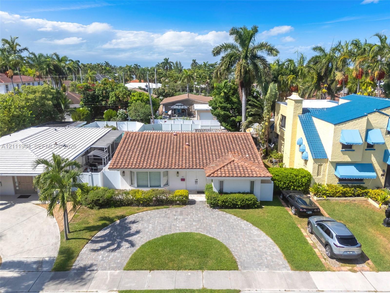 Single-story residence featuring a clay tile roof, a curved paver driveway, and landscaped front grounds