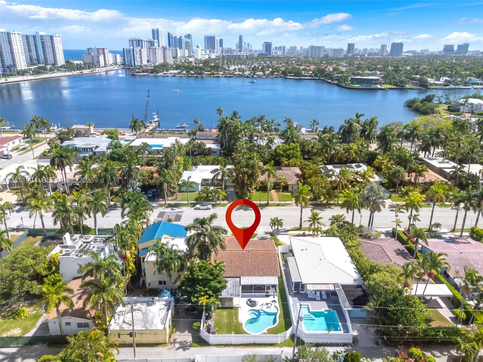 Residential property featuring a shingle-style roof, private swimming pool, concrete patio, and fenced backyard, situated within a coastal tropical landscape