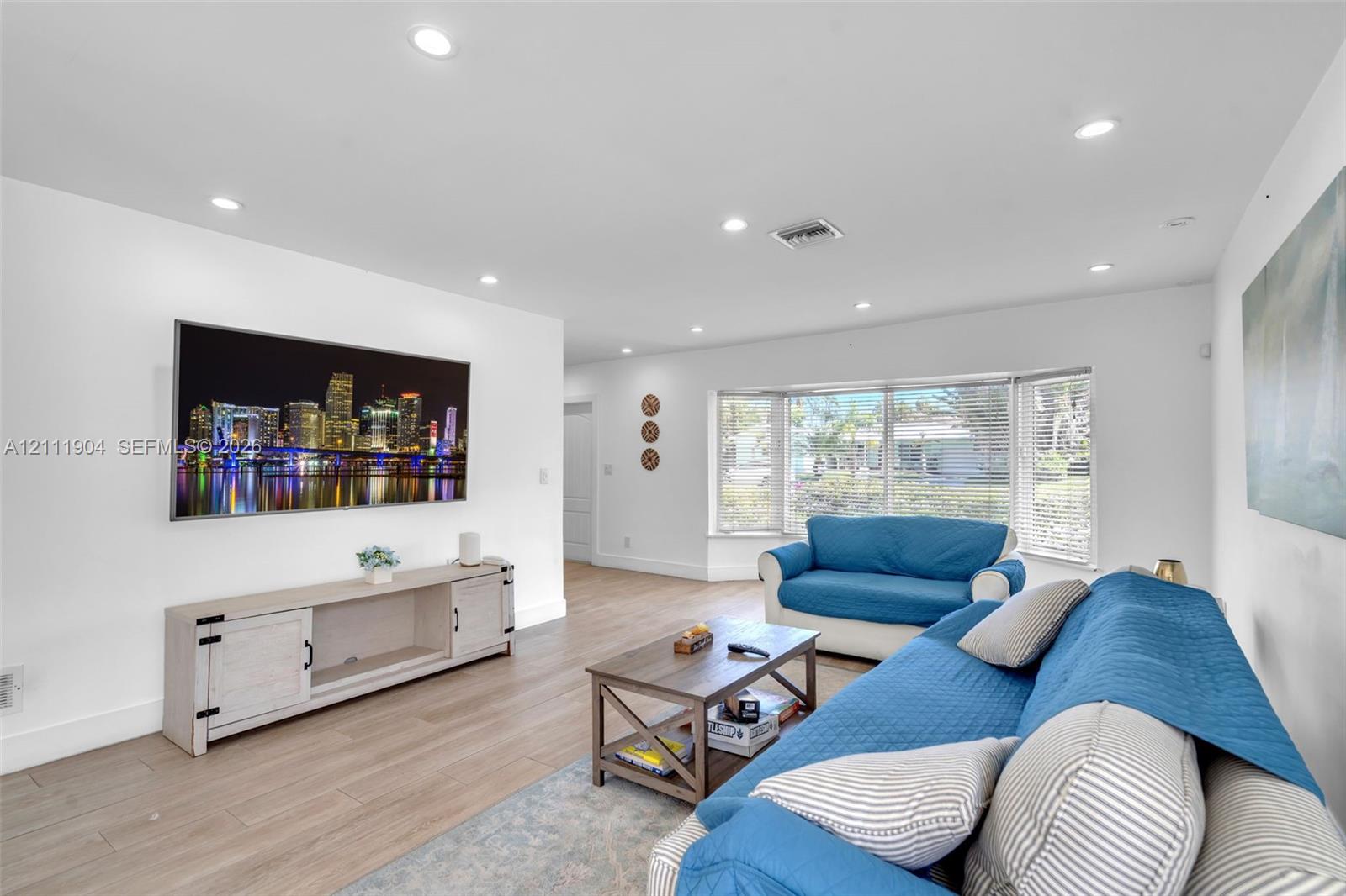 Living area featuring light-toned wood-finish flooring, recessed lighting, and a bay window