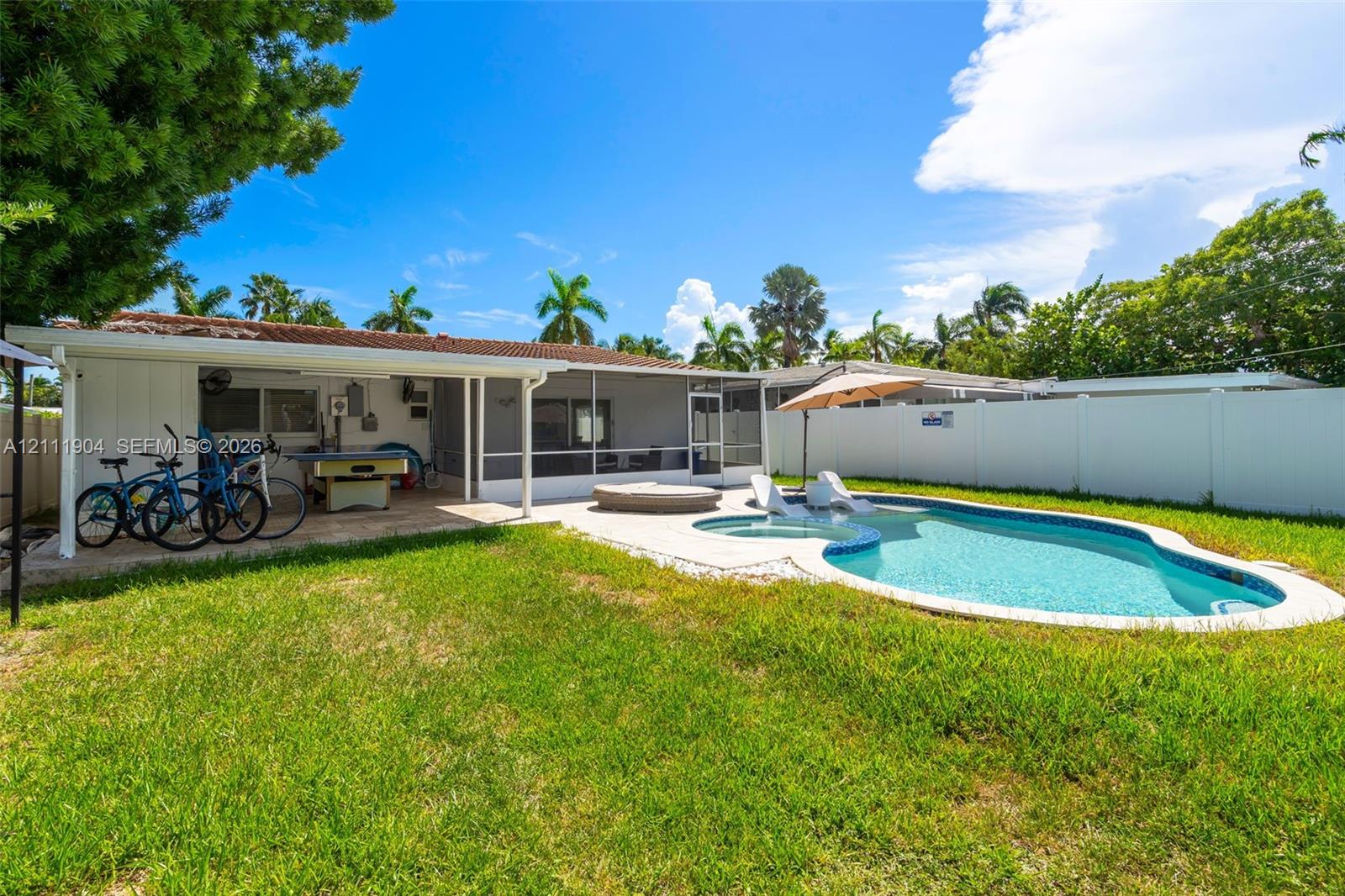 Outdoor living area featuring a covered lanai, screen-enclosed patio, in-ground pool with integrated spa, and full privacy fencing