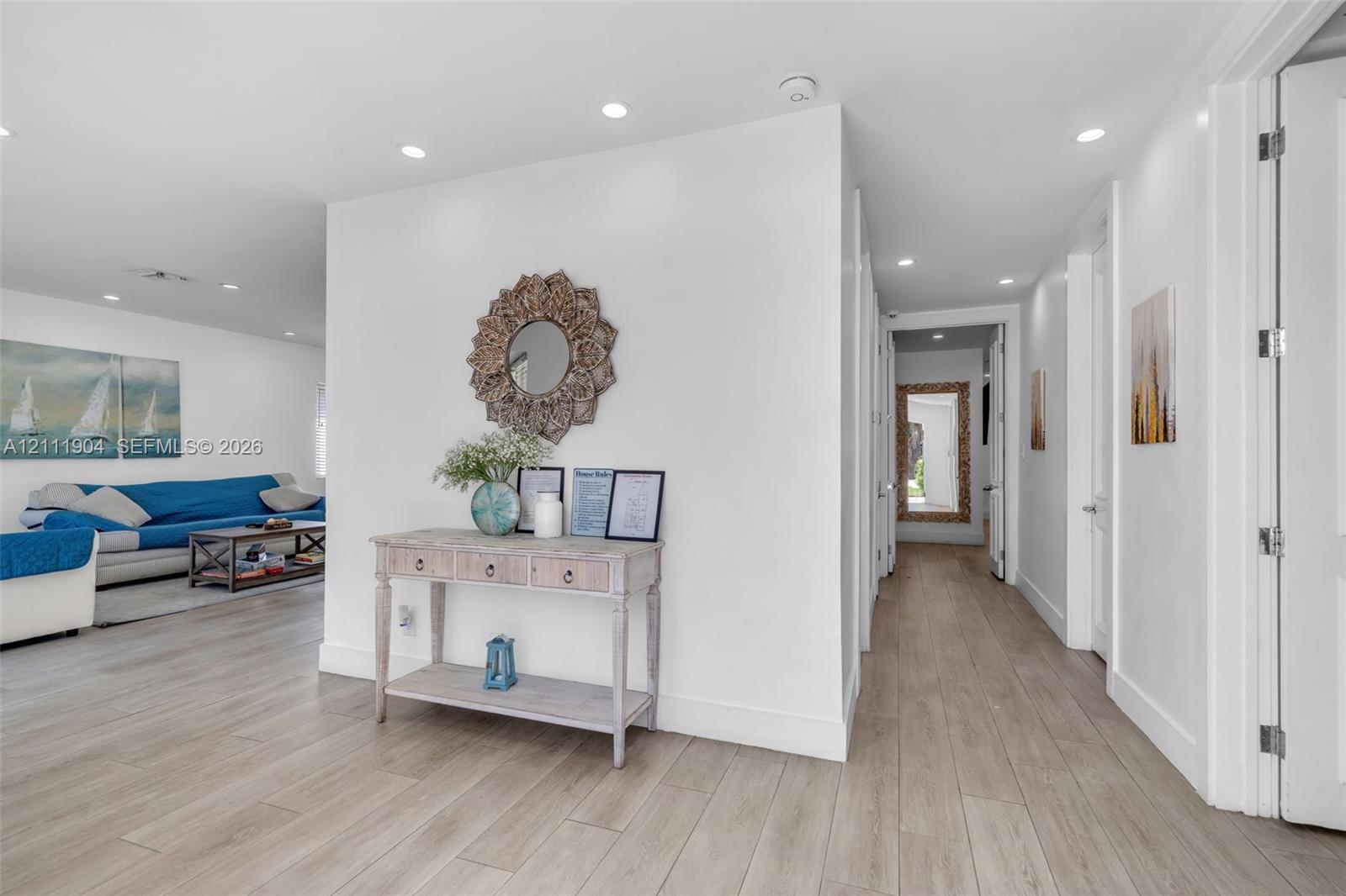 Interior hallway featuring wood-finish flooring, crisp white walls, and recessed ceiling lighting