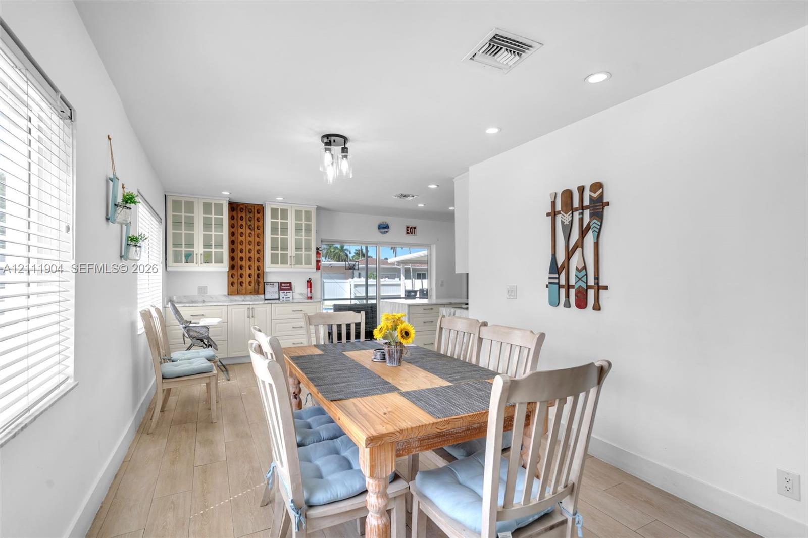 Kitchen area featuring white cabinetry with glass-paneled upper doors, wood-finish flooring, recessed lighting, and a multi-light fixture
