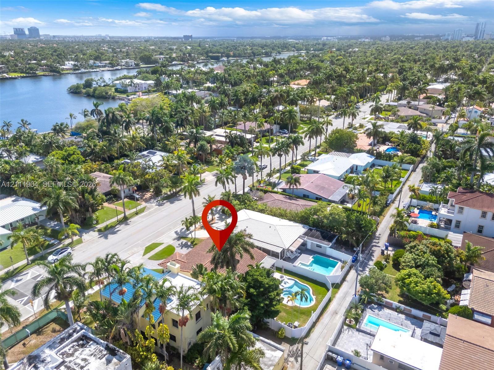 Aerial perspective showcasing a residential property with a tiled roof, a private swimming pool, and mature palm landscaping