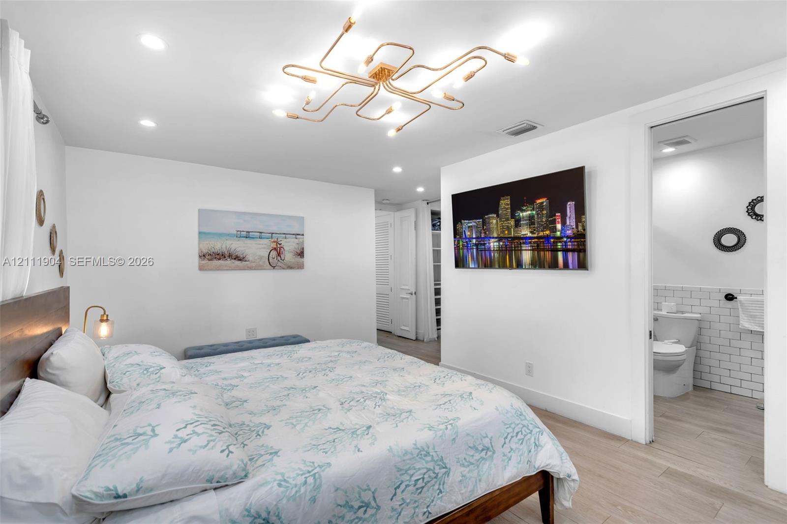 Contemporary interior space featuring light wood-finish flooring, a multi-arm geometric flush-mount light fixture, and recessed ceiling lighting