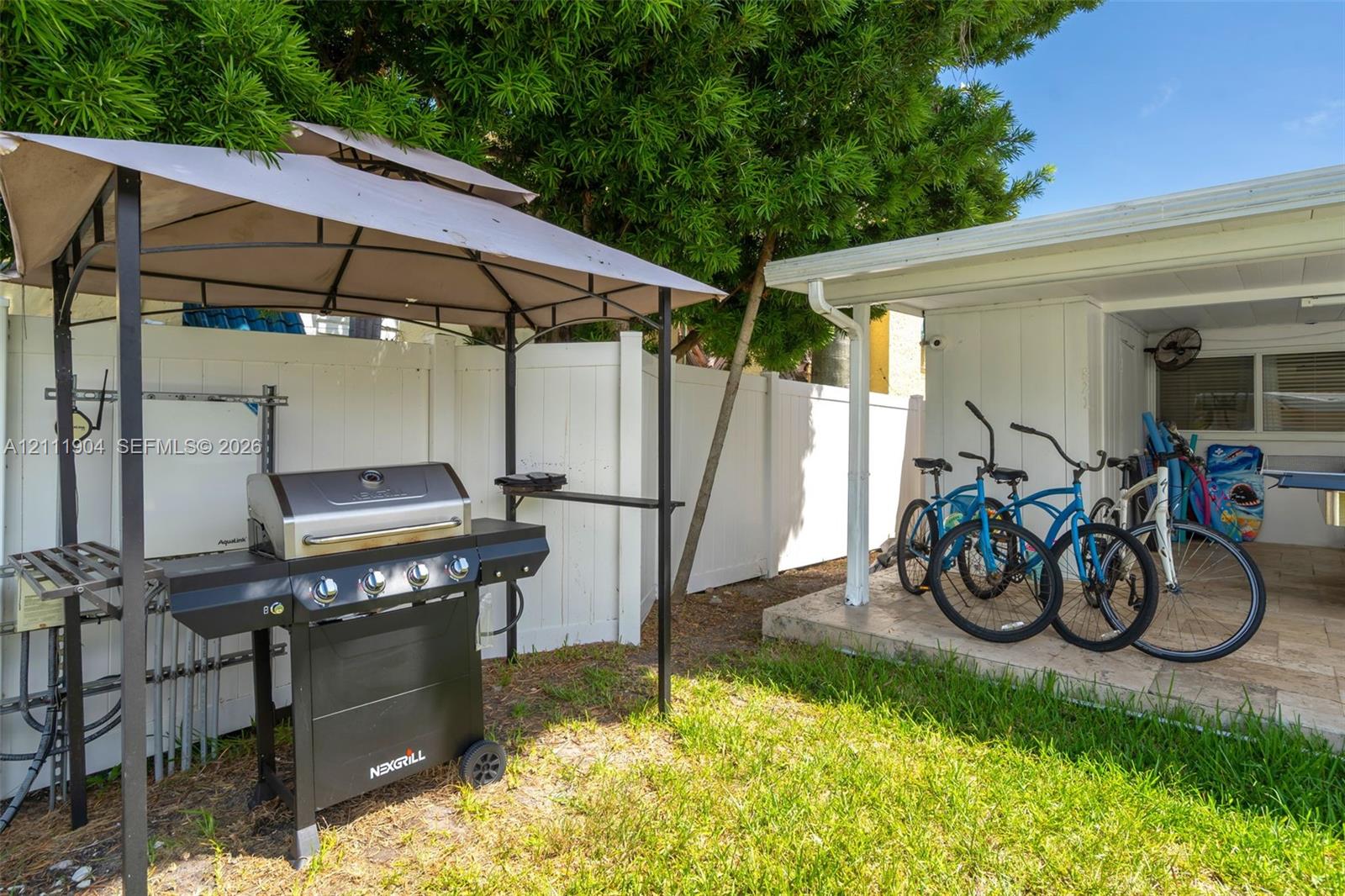 Private outdoor area featuring a white vinyl privacy fence, a concrete patio, and an integrated metal gazebo structure