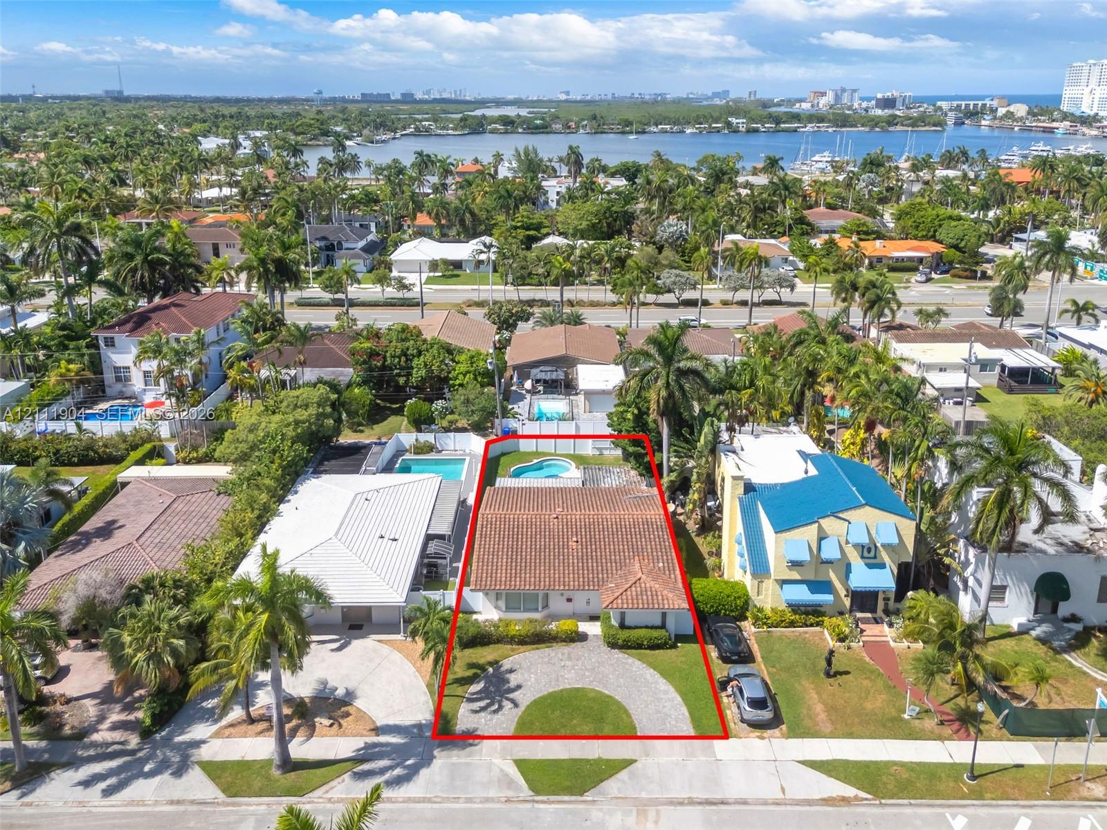 Single-story residence featuring a clay tile roof, a circular paver driveway, and a backyard swimming pool