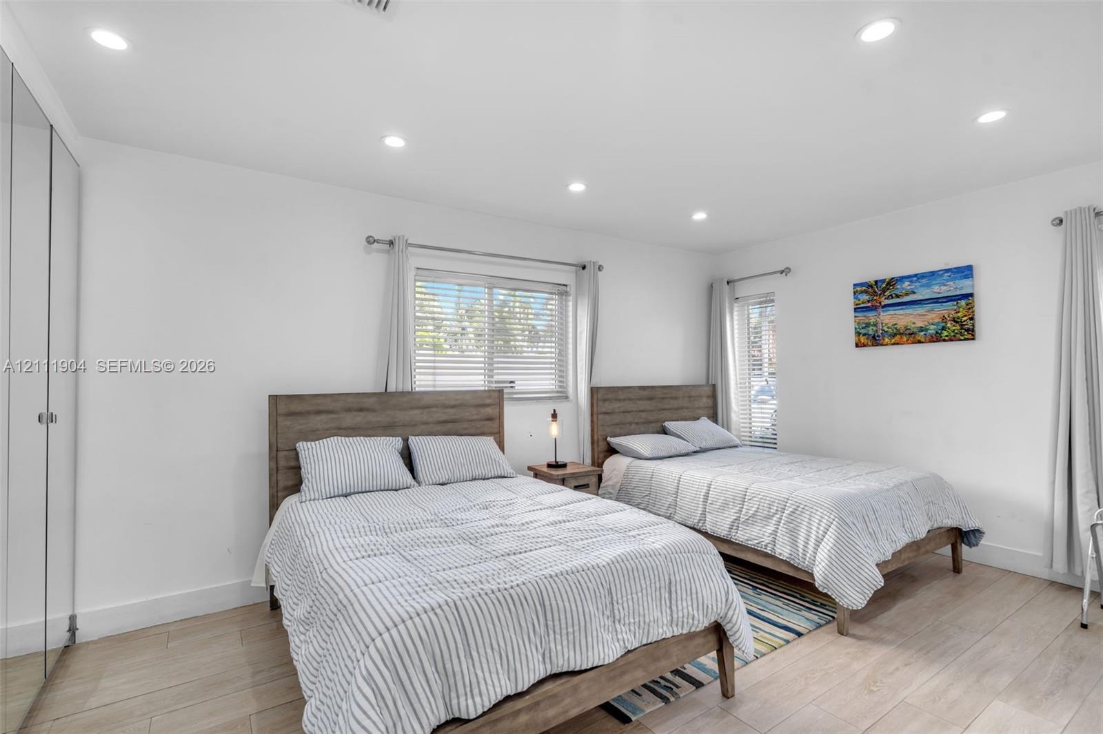 Neutral interior featuring recessed lighting, wood-finish flooring, and floor-to-ceiling mirrored closet doors