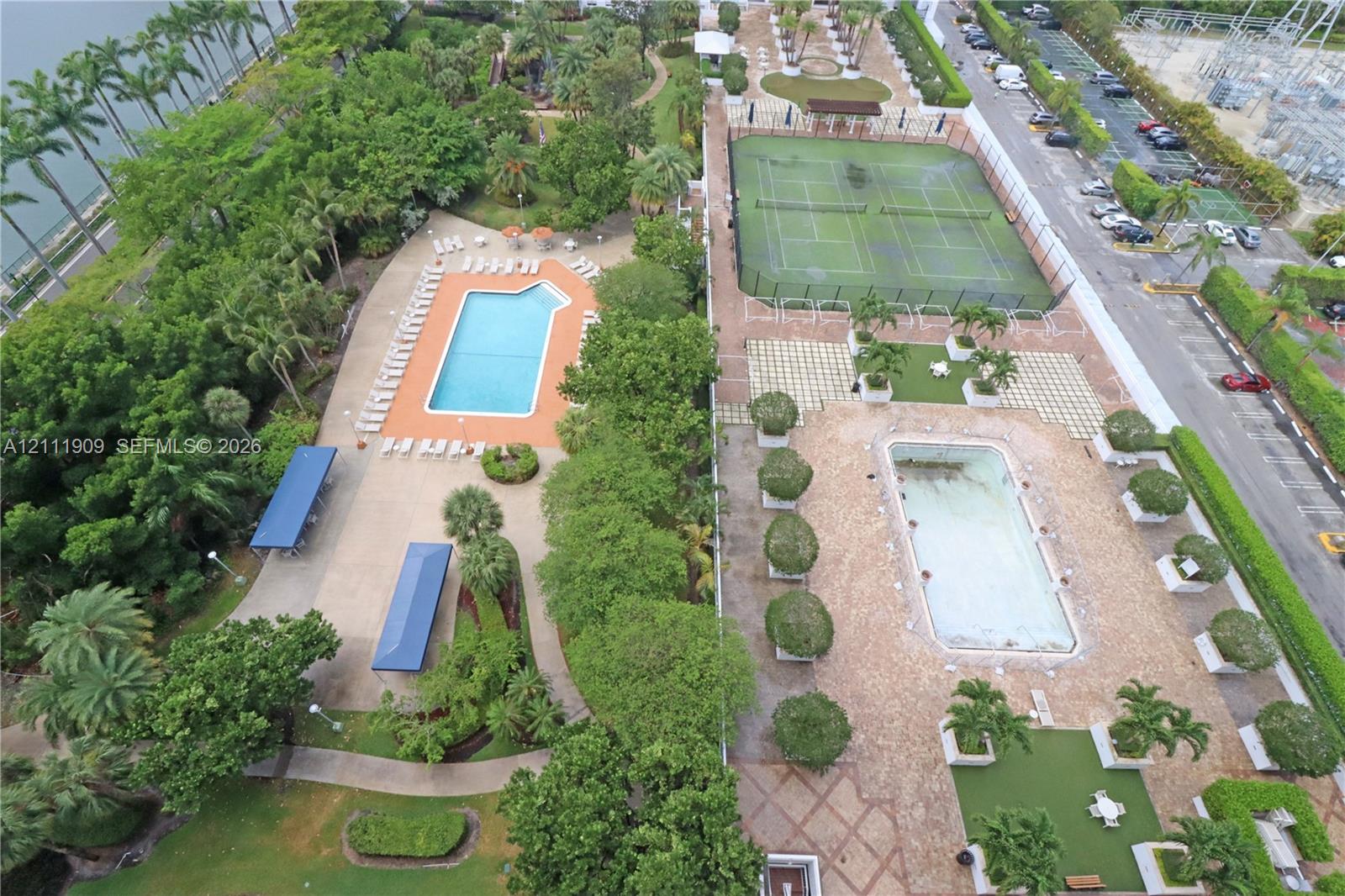 Common recreational grounds featuring two swimming pools, two tennis courts, paved walkways, and mature landscaping