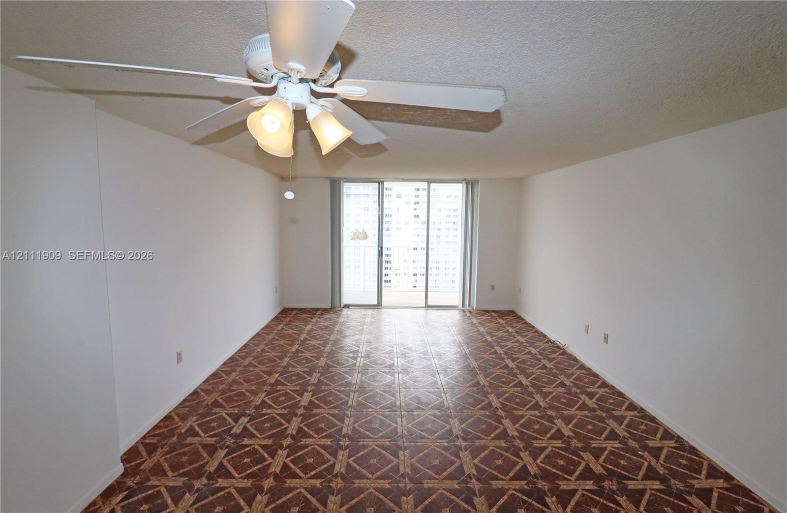 Interior space featuring geometric-patterned flooring, a ceiling fan with integrated lighting, and sliding glass doors leading to an exterior balcony