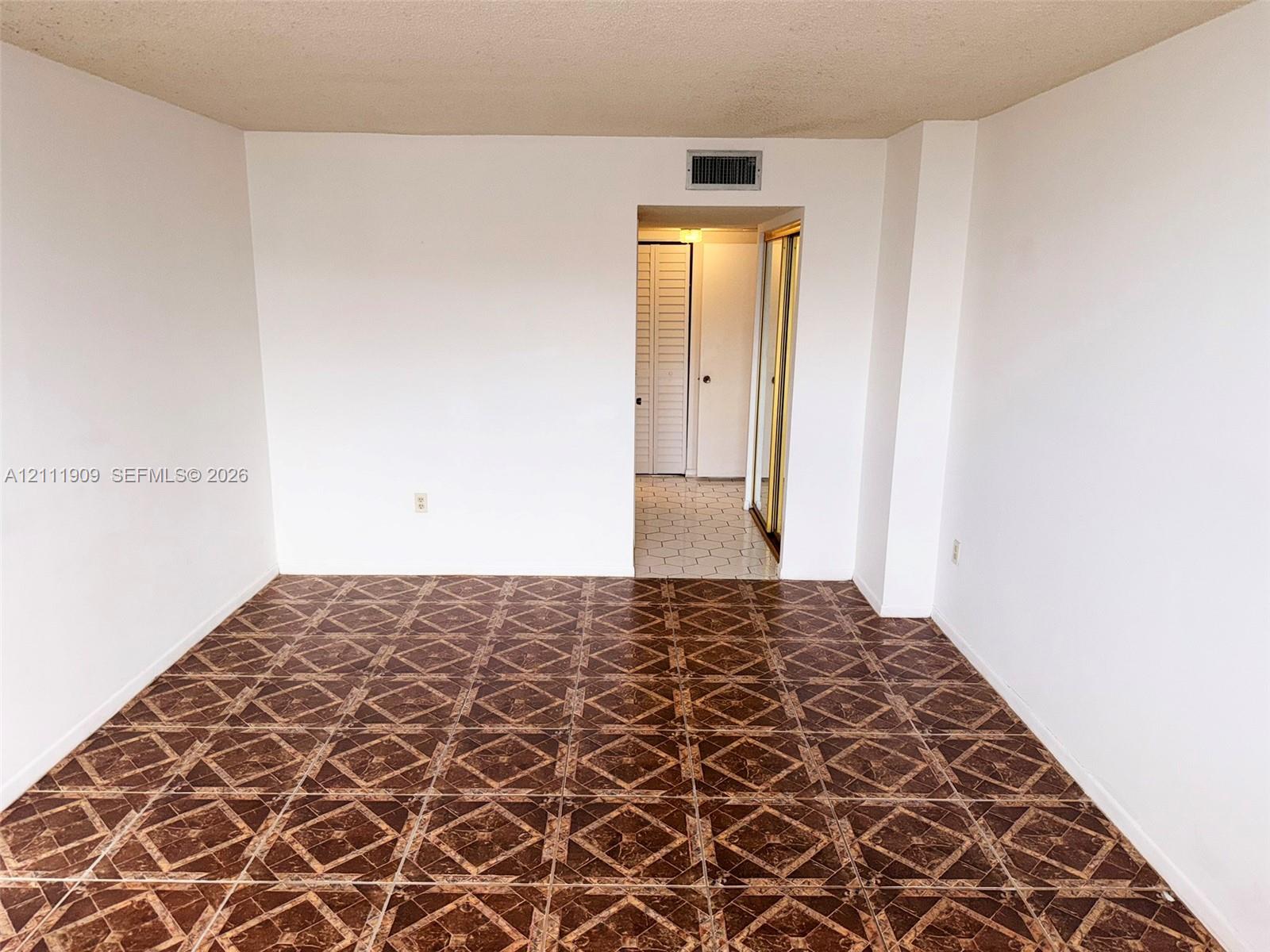 Interior room featuring dark, patterned tile flooring and smooth, white-painted walls