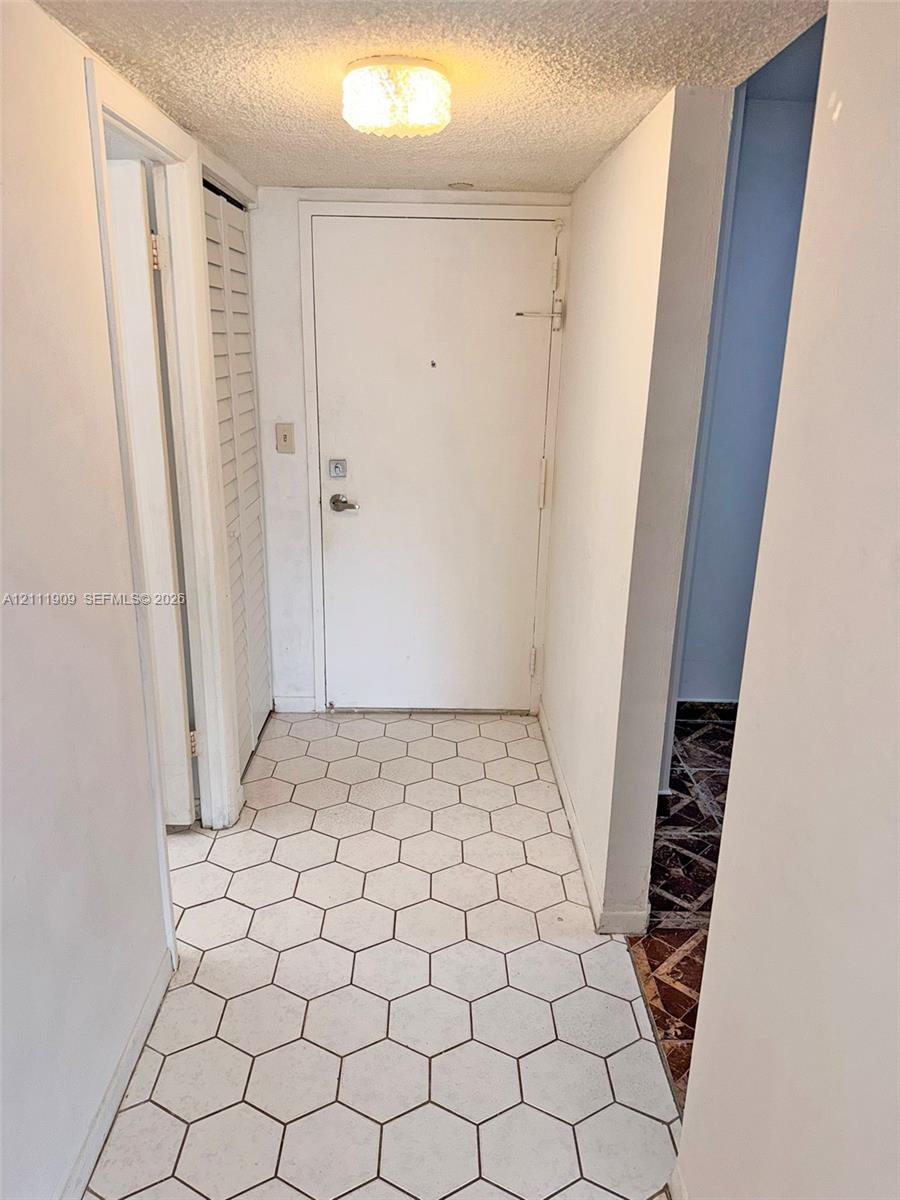 Entryway featuring white hexagonal floor tiling, a flush-mount drum ceiling light, and white paneled interior doors