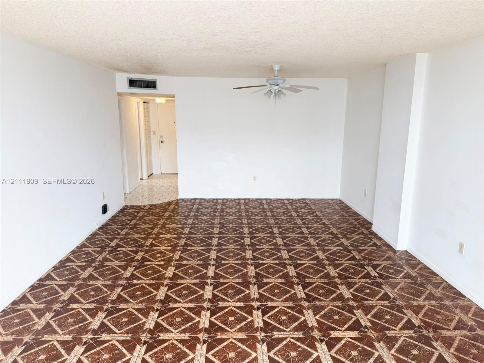 Spacious interior featuring patterned tile flooring, a centered ceiling fan with integrated lighting, and neutral wall finishes