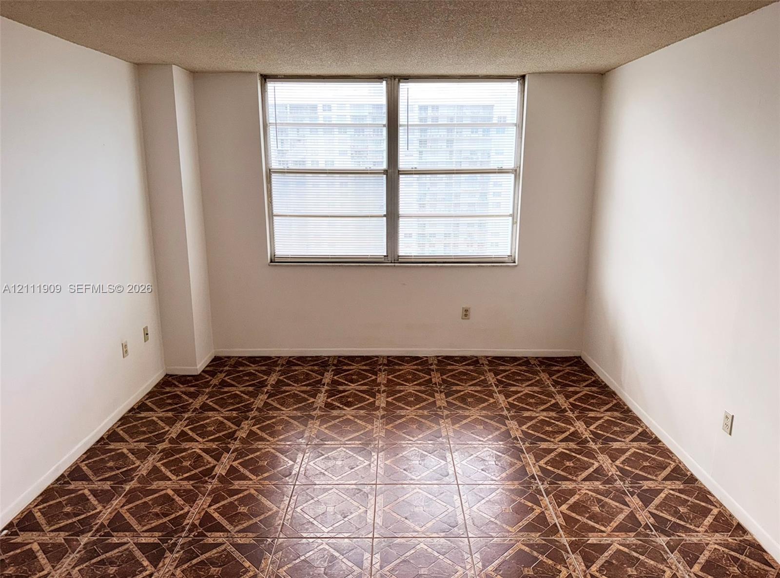 Interior space featuring patterned tile flooring, textured ceiling, and a large dual-pane window