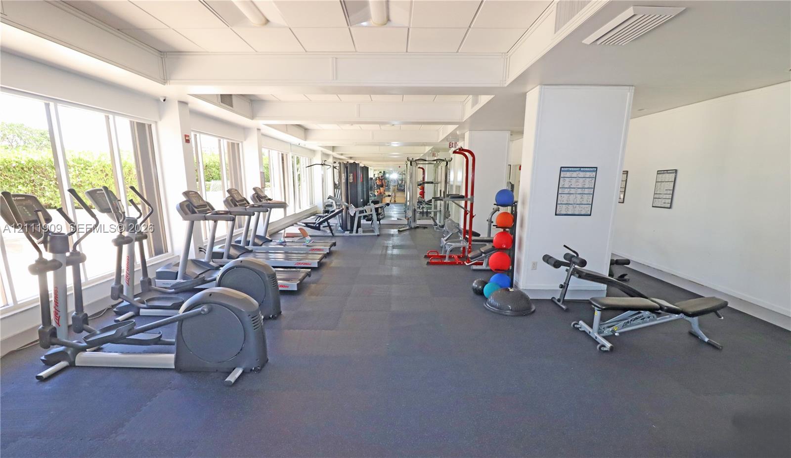 Fitness center featuring wall-to-wall rubber flooring, floor-to-ceiling windows, and recessed ceiling lighting
