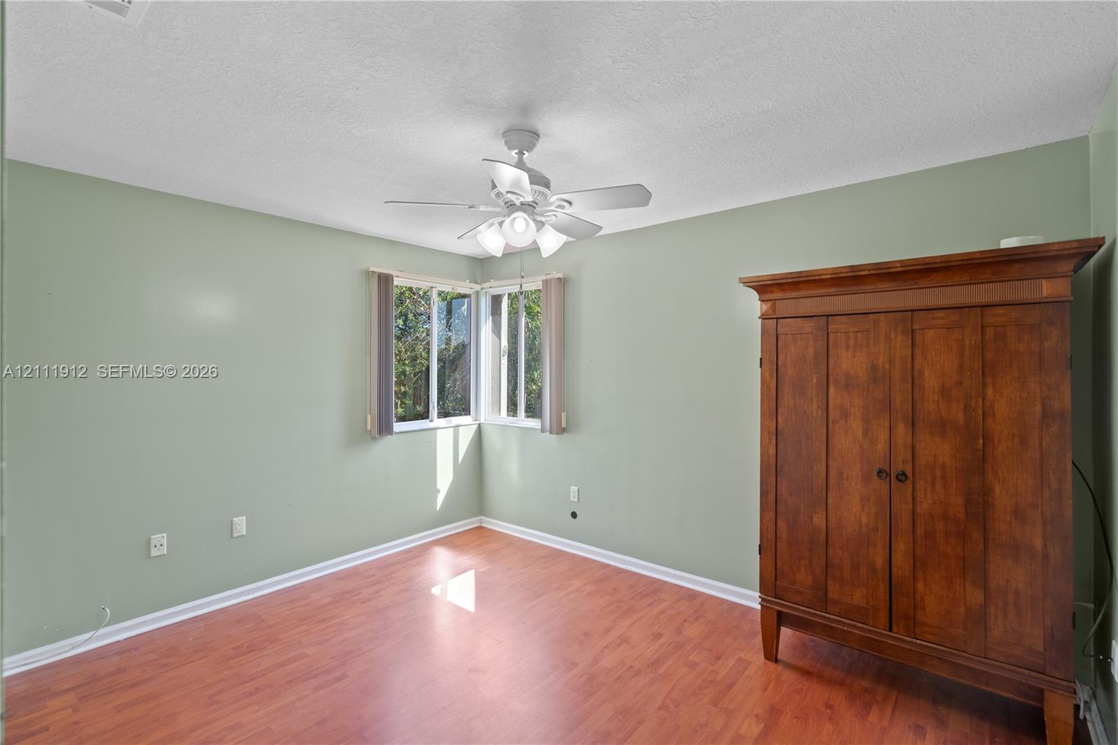 Interior space featuring wood-finish flooring, corner windows, and a ceiling-mounted light fixture with a fan