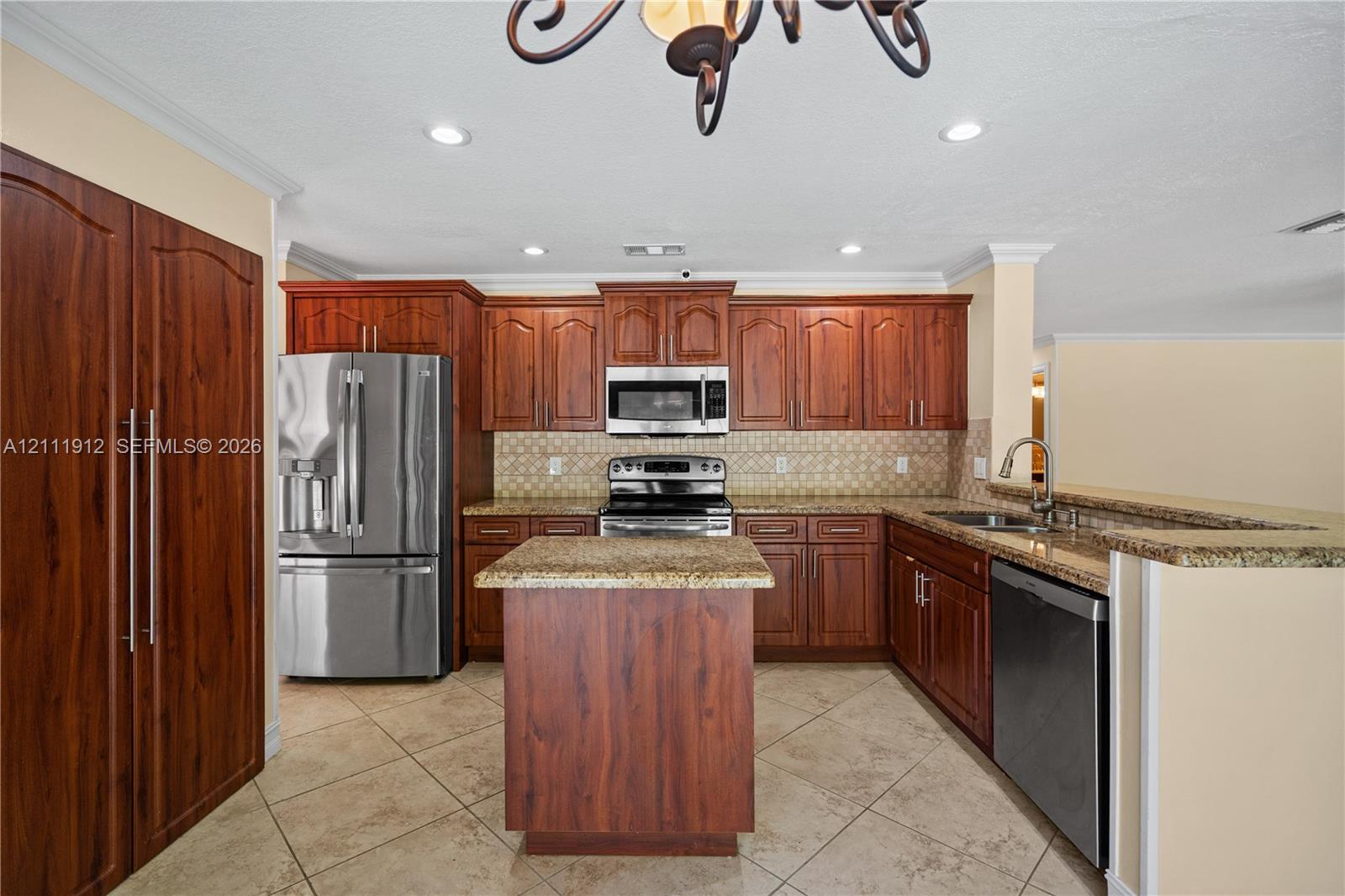 Kitchen featuring cherry-finish cabinetry, stainless steel appliances, stone-surface countertops, a center island, and tile flooring