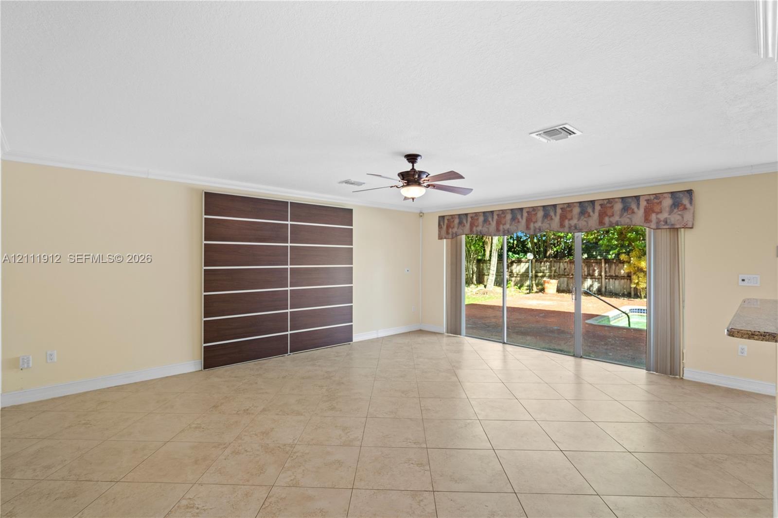 Tile flooring, custom floor-to-ceiling sliding cabinetry, ceiling fan, and oversized sliding glass doors