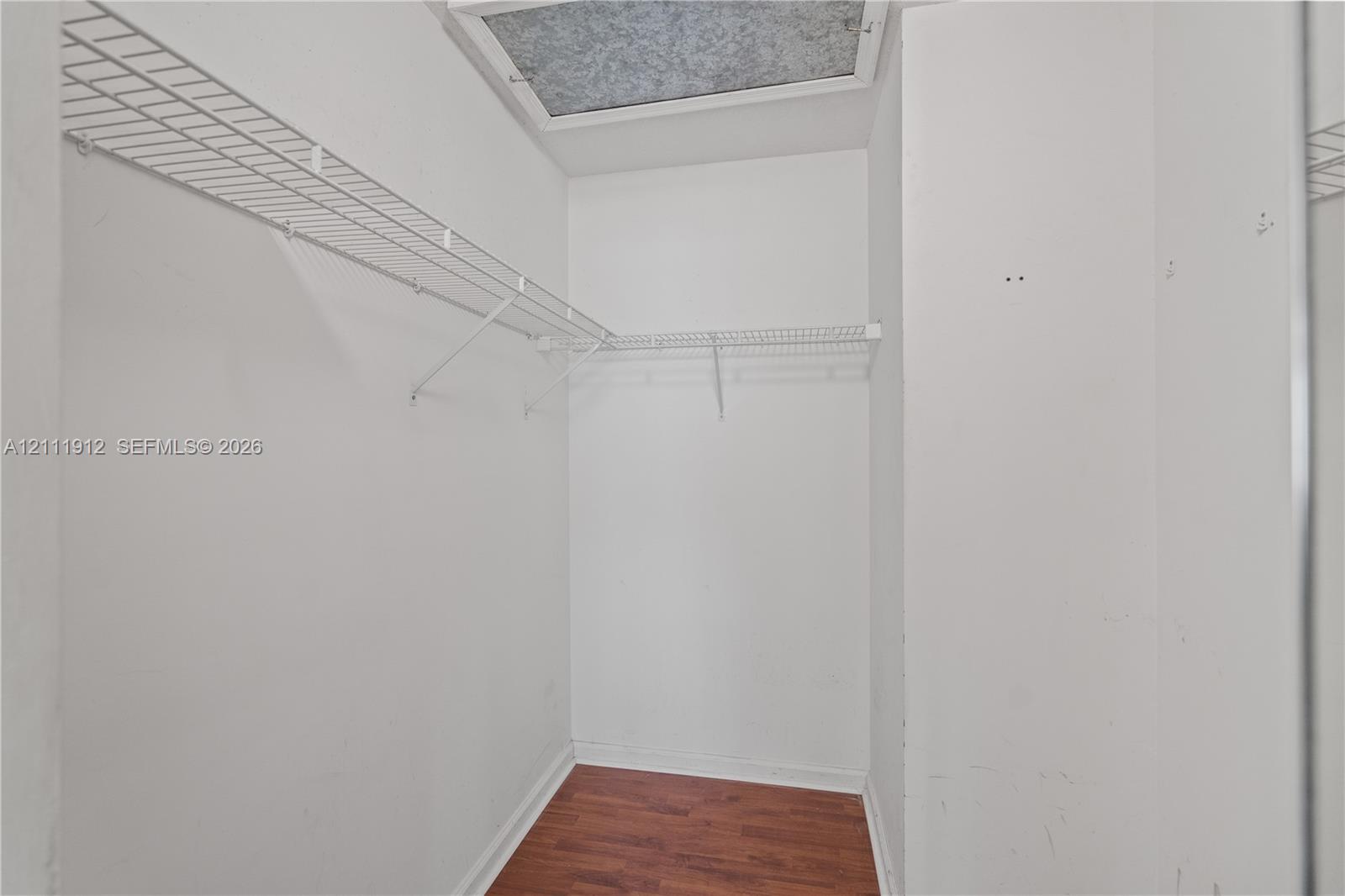 Walk-in storage space featuring wire shelving and wood-finish flooring