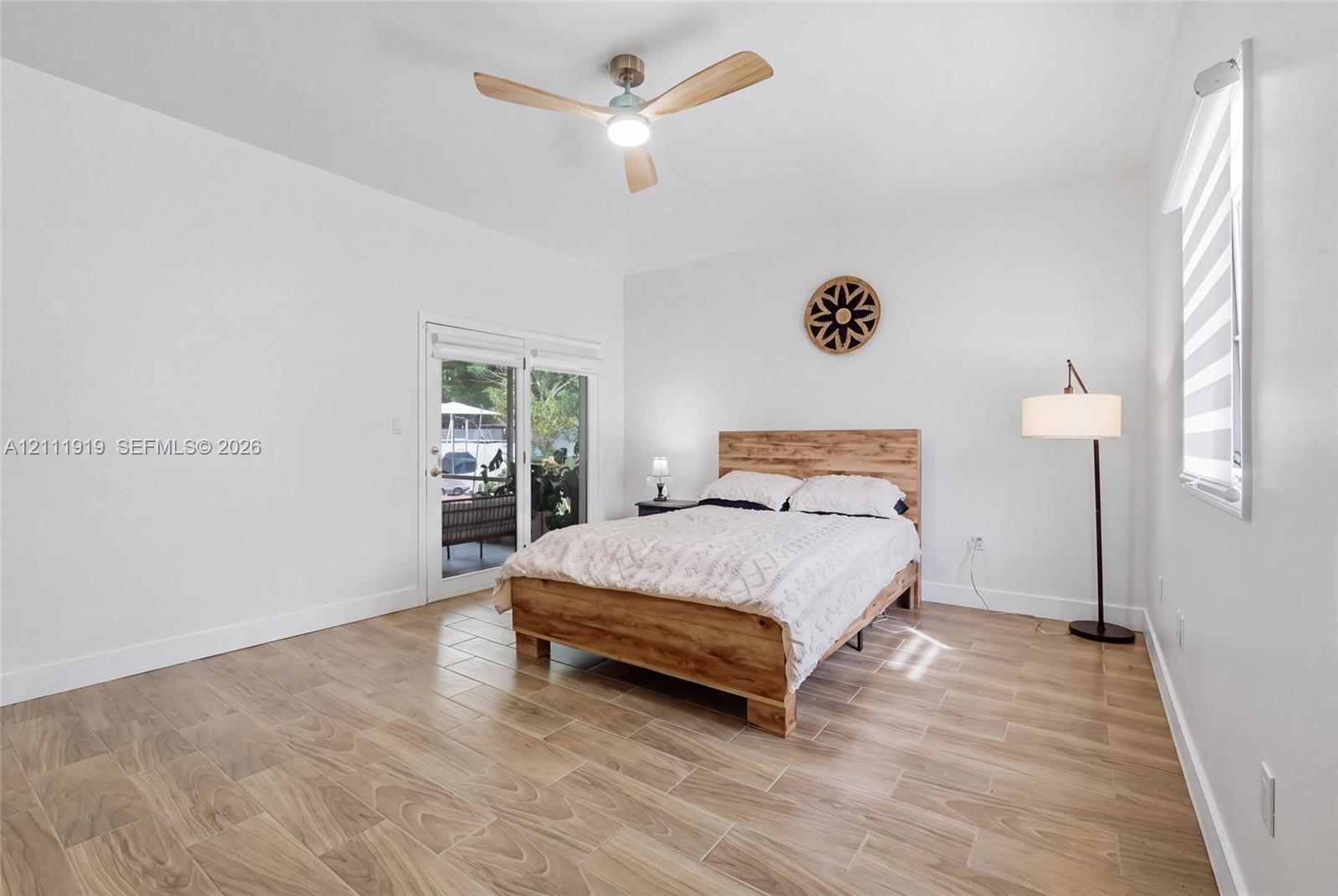 Wood-finish tile flooring, recessed ceiling fan with integrated lighting, and glass-paneled sliding door