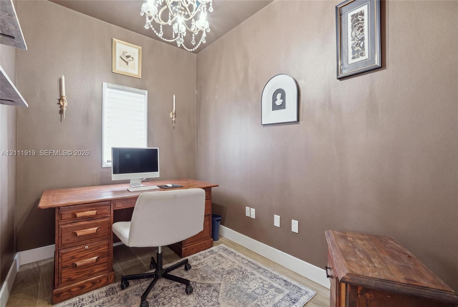 Interior space featuring an ornate crystal chandelier, wall-mounted candle-style light fixtures, and wood-finish flooring