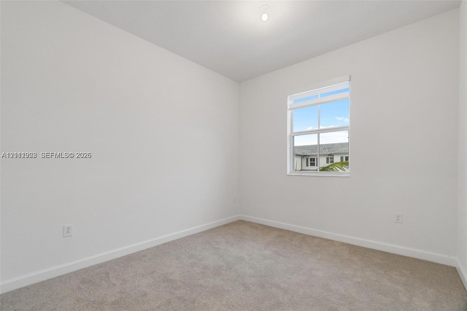 Neutral-toned interior room featuring wall-to-wall carpeting, white walls, and a single-hung window with fitted blinds