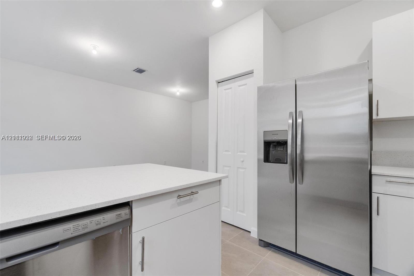 Kitchen featuring white shaker-style cabinetry, quartz countertops, stainless steel side-by-side refrigerator, stainless steel dishwasher, and recessed ceiling lighting Kitchen featuring white shaker-style cabinetry, quartz countertops, stainless steel side-by-side refrigerator, stainless steel dishwasher, and recessed ceiling lighting