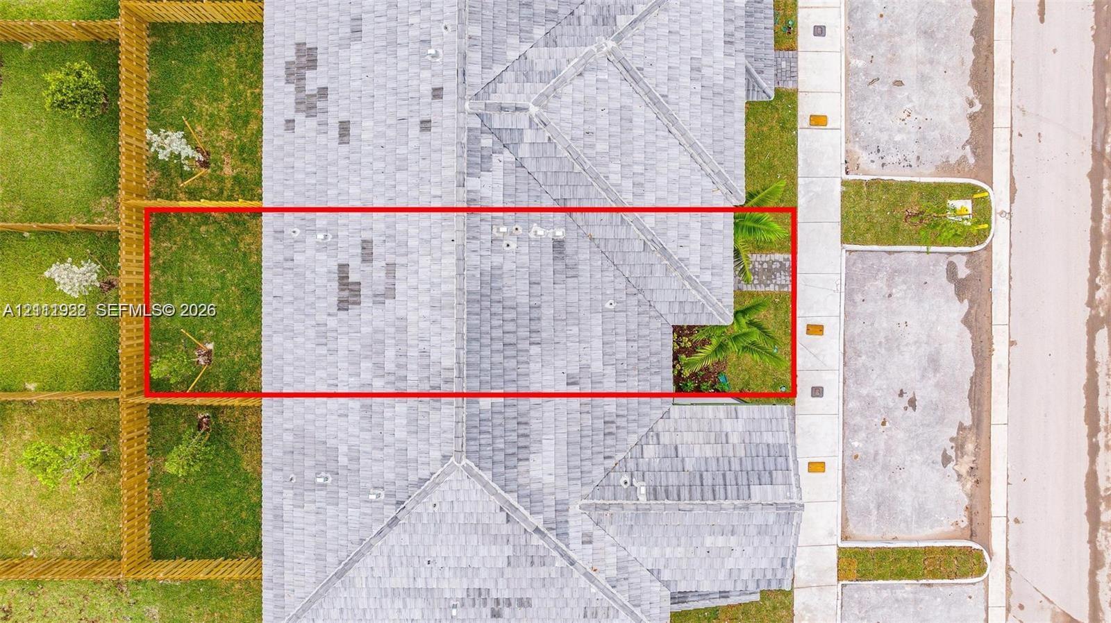 Aerial view featuring an asphalt shingle roof, a fenced perimeter, and a grass-covered outdoor area