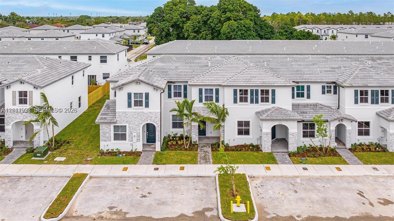 Multi-unit residential complex featuring stucco siding, stone veneer accents, concrete tile roofing, and decorative exterior shutters Multi-unit residential complex featuring stucco siding, stone veneer accents, concrete tile roofing, and decorative exterior shutters
