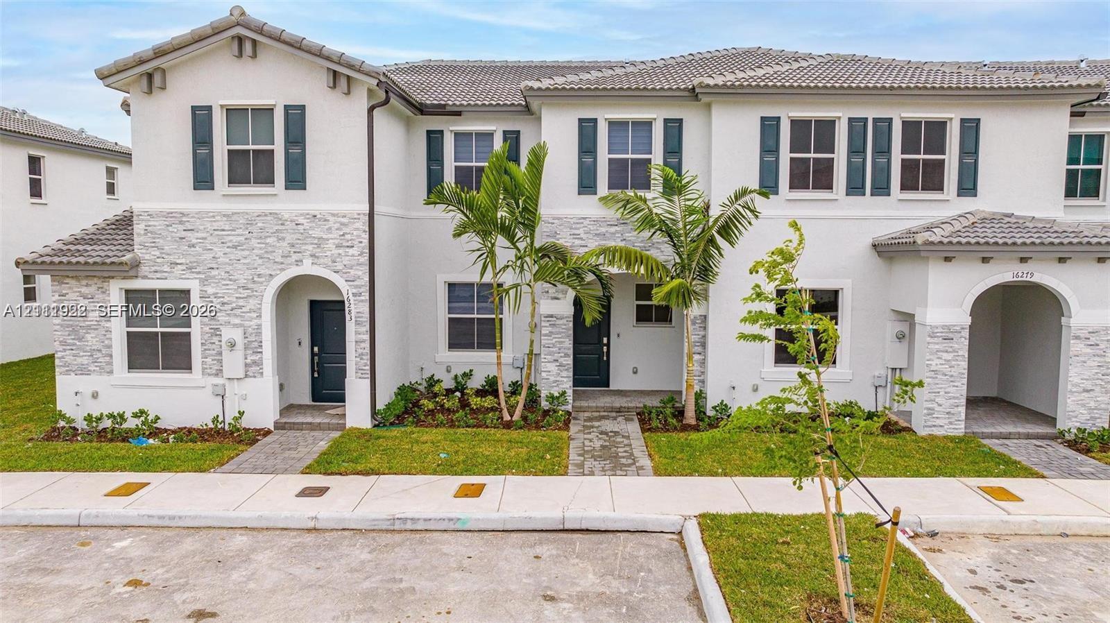 Two-story exterior featuring a light-toned stucco finish, decorative stone veneer accents, multi-pane windows with dark shutters, and arched entryway detailing Two-story exterior featuring a light-toned stucco finish, decorative stone veneer accents, multi-pane windows with dark shutters, and arched entryway detailing
