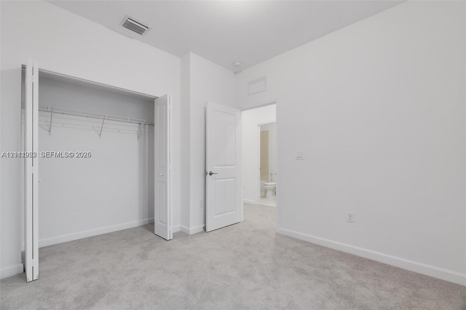 Neutral wall color, wall-to-wall carpeting, bi-fold closet doors with built-in shelving, and solid-core interior doors