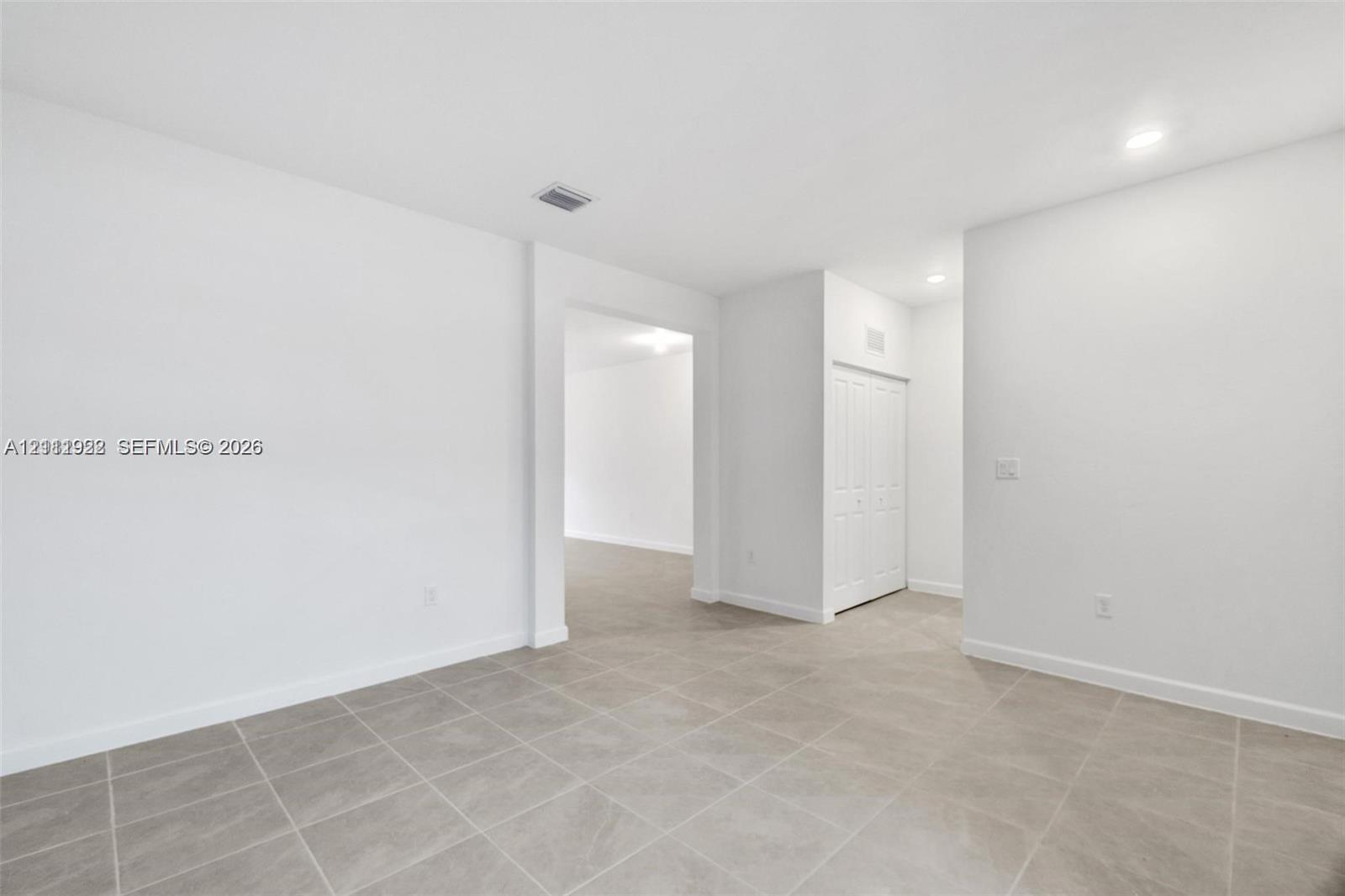 Neutral-toned tile flooring, recessed ceiling lighting, and built-in closet with multi-panel doors Neutral-toned tile flooring, recessed ceiling lighting, and built-in closet with multi-panel doors