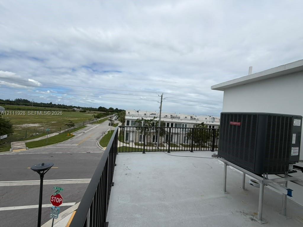 Rooftop terrace featuring a flat surface, metal railing, and external HVAC unit