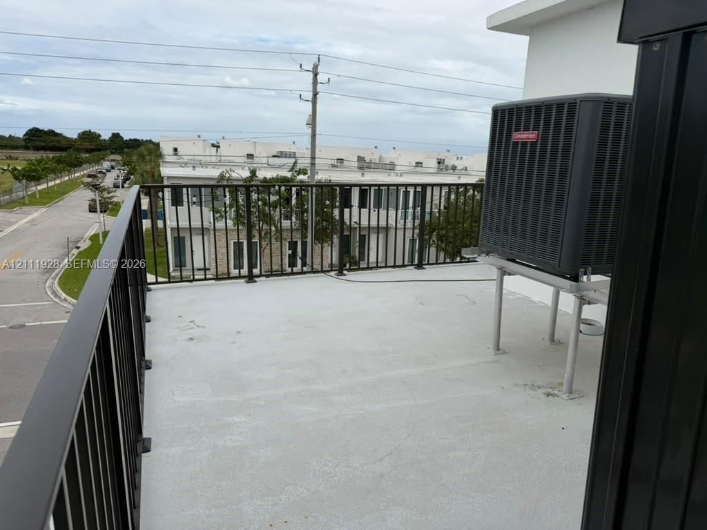 Elevated outdoor deck featuring a concrete surface, black metal railings, and a mounted HVAC unit