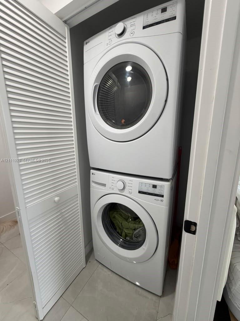 Stacked white front-load laundry unit enclosed behind bi-fold louvered doors