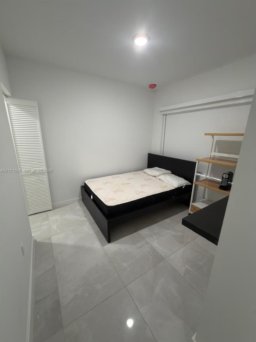 Neutral-toned, large-format tile flooring and a white louvered-door closet