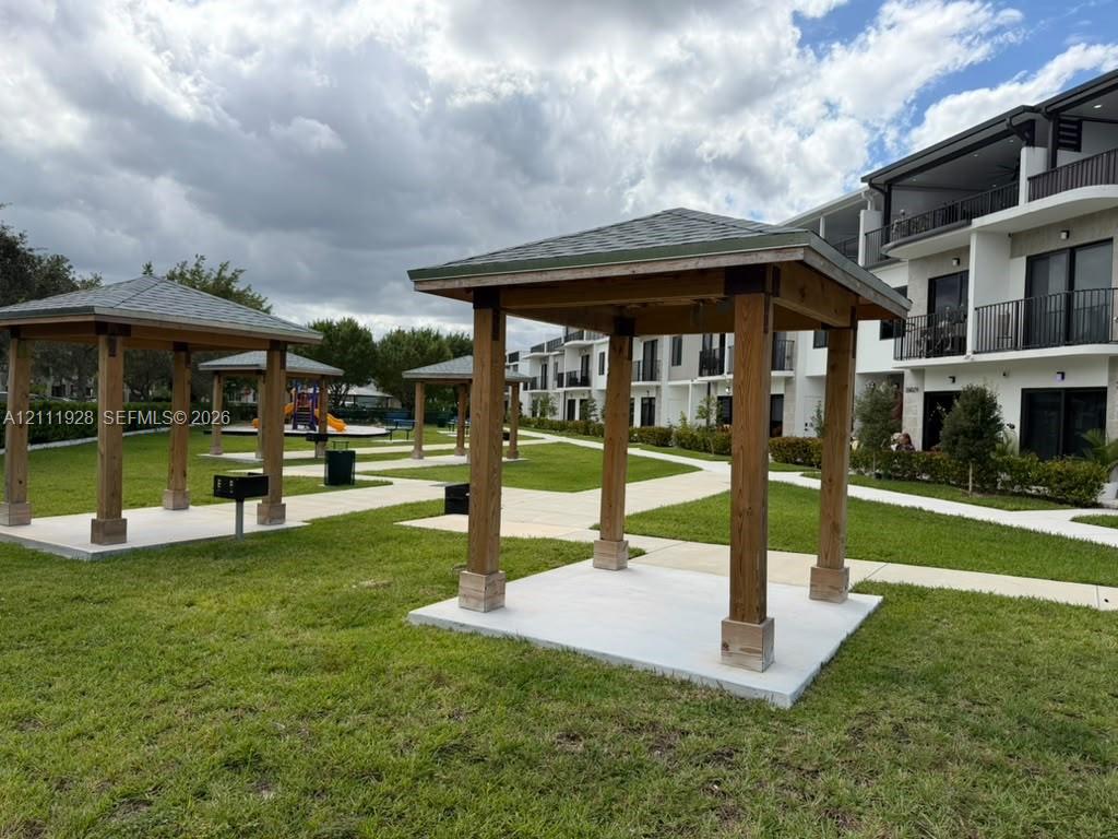 Exterior grounds featuring multiple wood-post gazebos, shingled roofing, concrete pads, and integrated charcoal grills set within a landscaped lawn Exterior grounds featuring multiple wood-post gazebos, shingled roofing, concrete pads, and integrated charcoal grills set within a landscaped lawn
